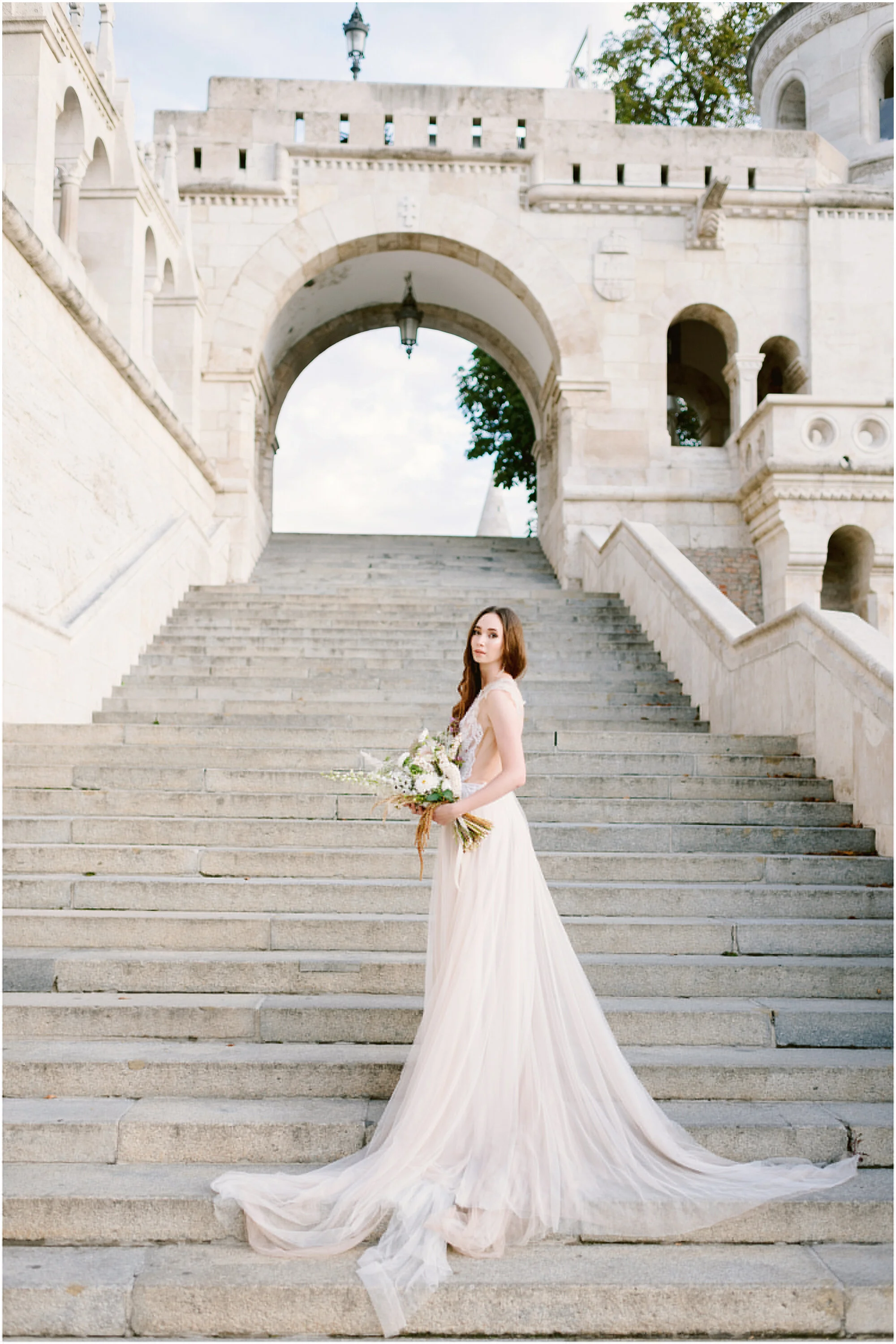 Elegant bridal portrait on stone steps before an ornate arched building
