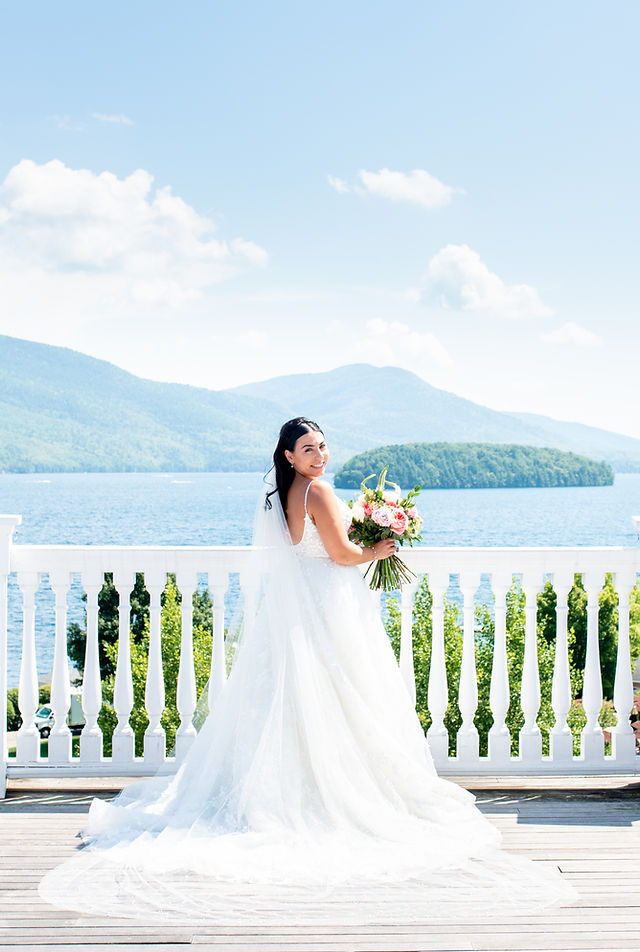 Bright outdoor bridal portrait by a blue lake and green mountains
