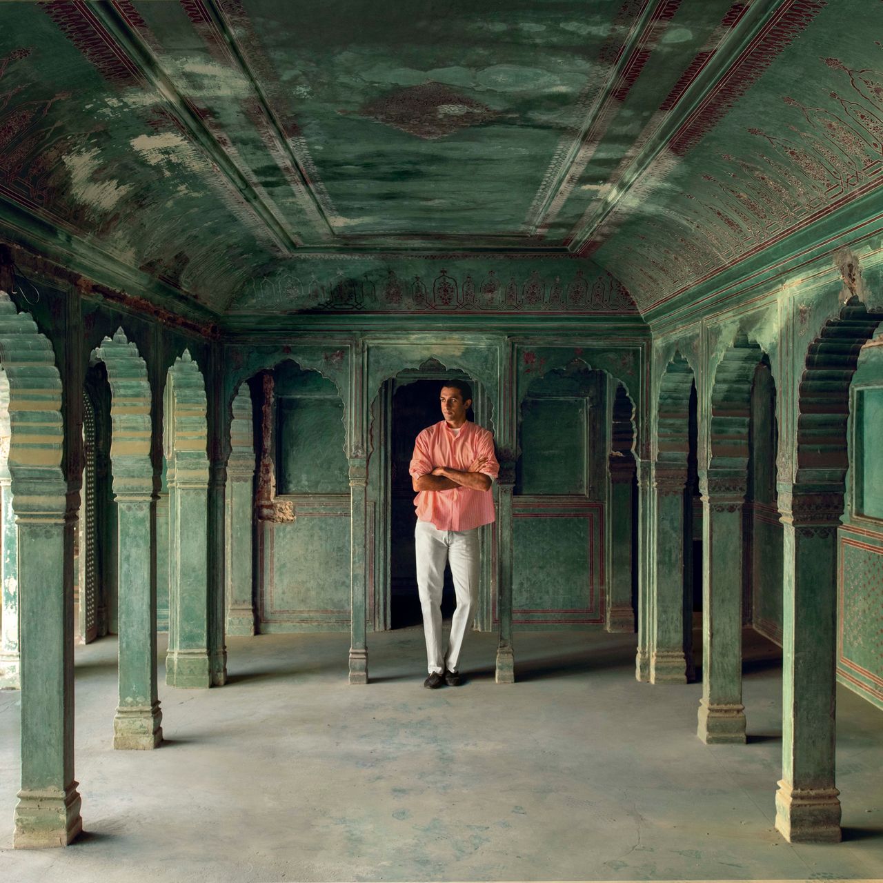 Historic teal and red arched hall with a person standing in the space