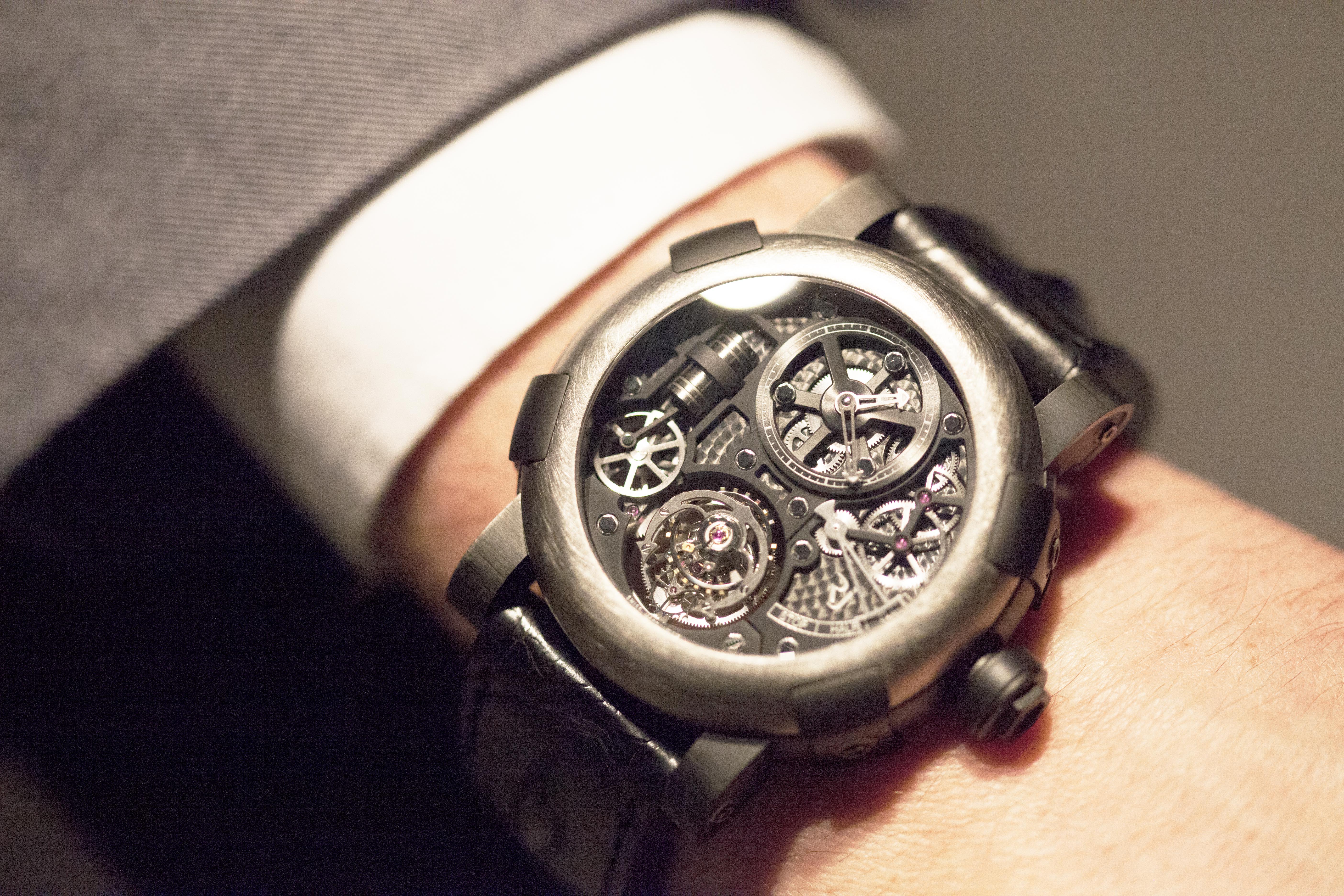 Mechanical wristwatch with exposed gears worn with a white shirt cuff
