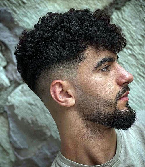 Side profile with curly haircut, high fade, and full beard