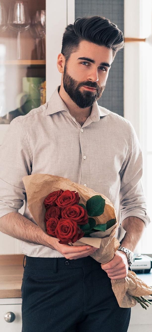 Stylish man holding red roses wrapped in brown paper